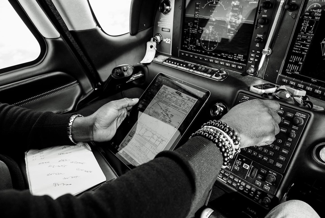 Black and white cockpit image showing a pilot's hands, a tablet briefing and flight instruments during preparation — Ukraine Air Rescue Mission 2022.